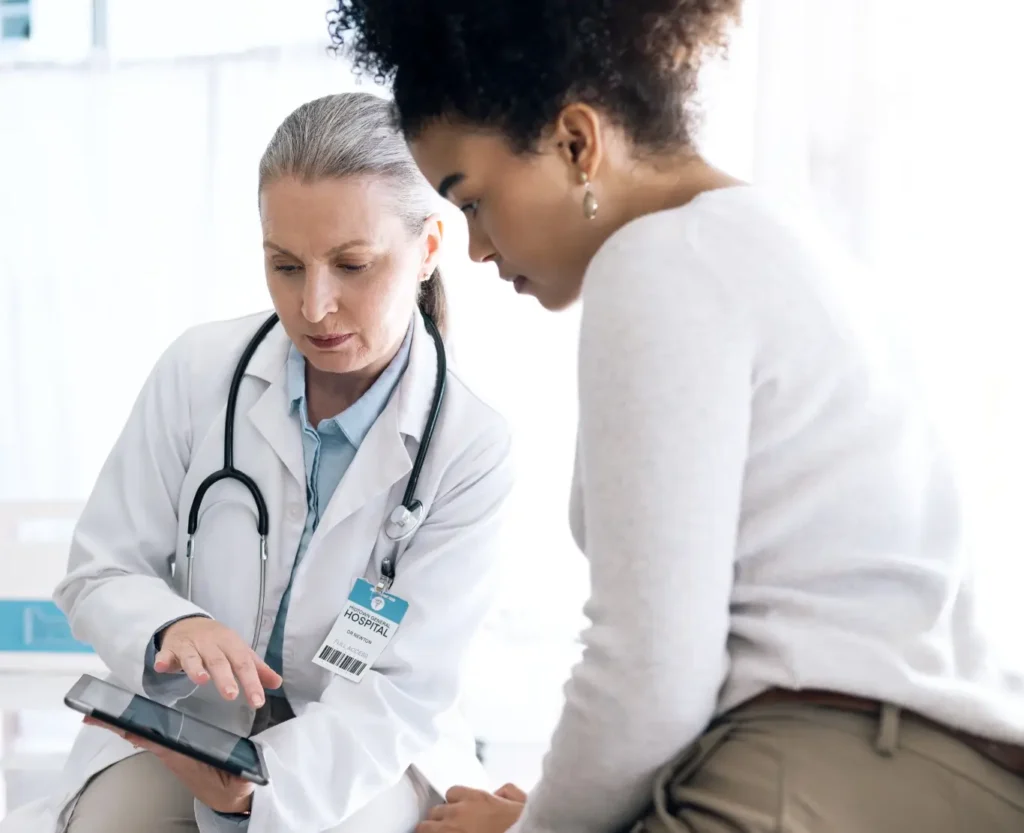 A doctor in conversation with her patient showing options on a tablet device.